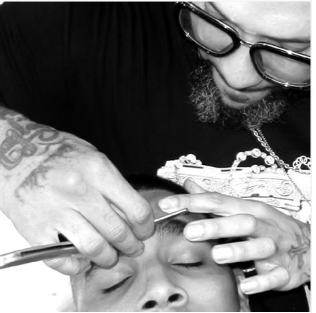 Kev shaping a client's eyebrow with a straight razor