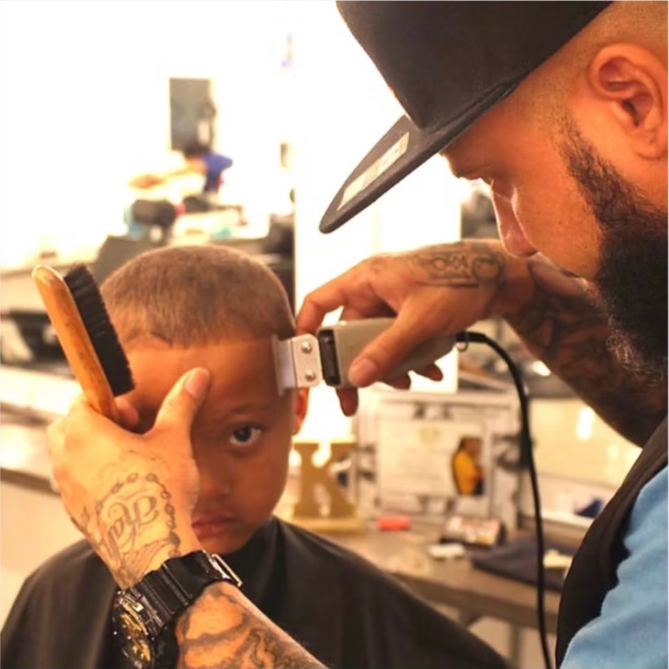 Kev clipper-cutting a young boy's hair in the barbershop