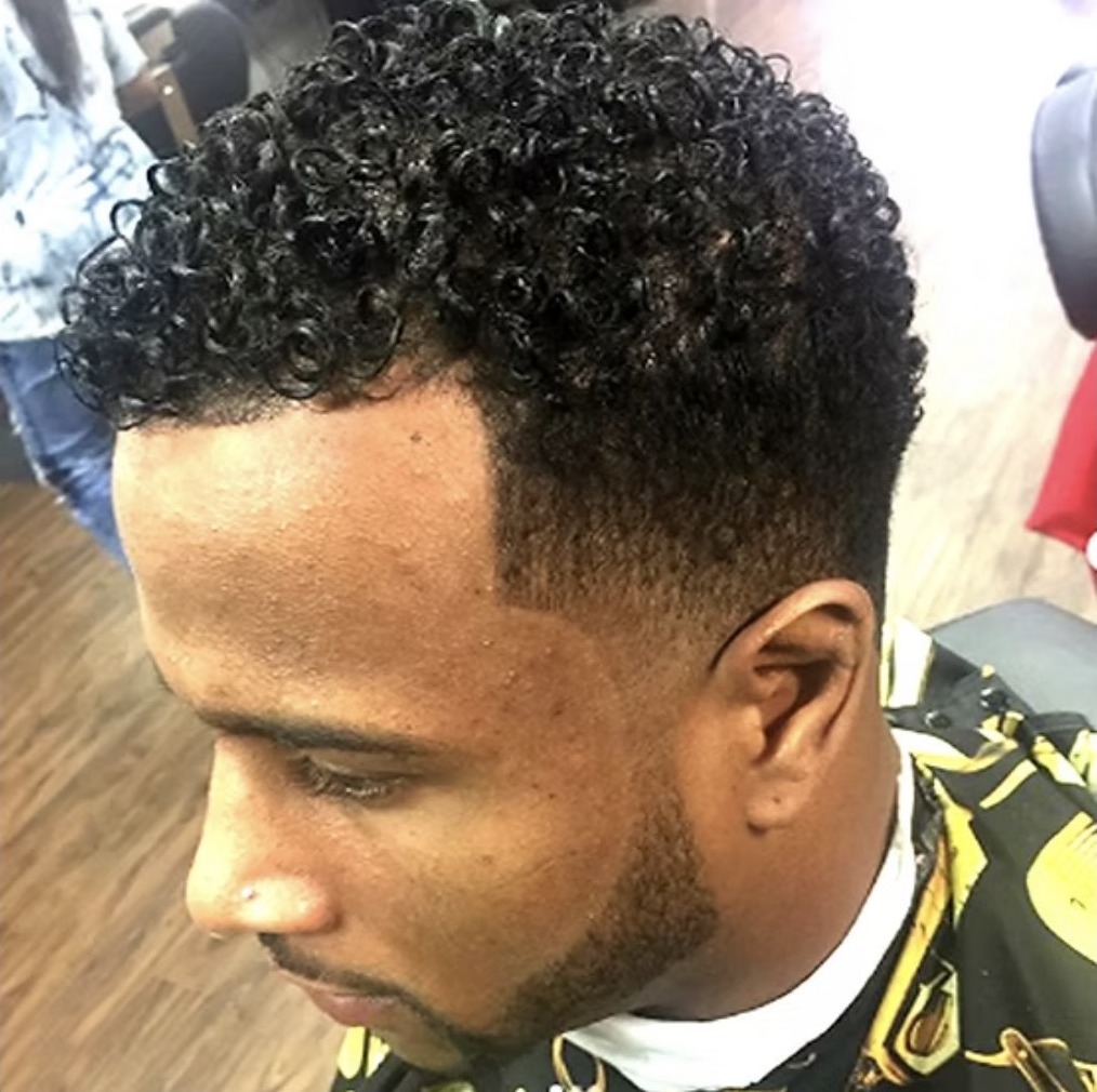 Client with a curly texturizer finish and a sharp taper fade