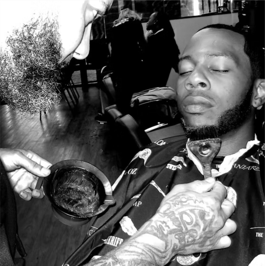 Black and white photo of a client reclined in the chair as color is mixed for a Black Caesar cut
